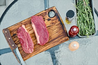 Top view of raw striploin beef steak on wooden cutting board