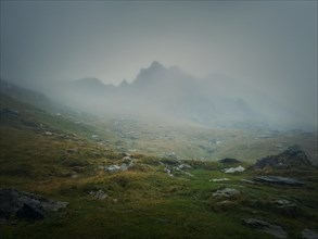 Mountain peak seen through the dense fog. Rainy scene in the mounts