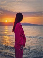Portrait of a young woman as meets the dawn at the sea. Beautiful sunrise at the Bulgarian coastline of Black Sea