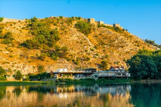 View of the Rozafa Castle on top of the mountain from a boat on a sightseeing excursion on Lake Shkoder in Shiroka. Albania