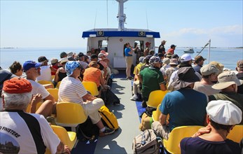 Sun deck of a tourist ship with tourists and crew member giving explanations via microphone
