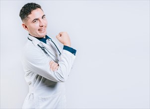 Doctor showing muscle and smiling isolated. Young doctor showing strength with his arm