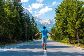 A tourist in summer walking on the road in the Valbona valley enjoying the freedom