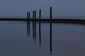 Poles with water reflection at dusk on the beach of Cuxhaven
