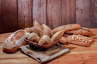Assortment of loaves and loaves of bread of different types of seeds on wooden table and ears of wheat