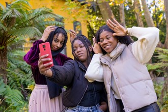Funny african and muslim friends grimacing and gesturing while taking a selfie standing in an urban park