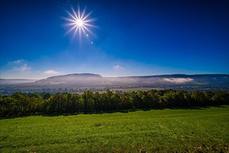 Fog below the core mountains above the village Kunitz near Jena with sun star and blue sky