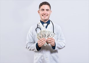 Latin young doctor holding money isolated. Cheerful doctor showing dollars isolated