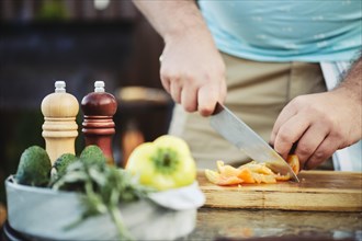 Unrecognizable man slicing sweet bell pepper for vegetable salad