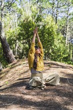 Woman about to meditate with hands clasped to the sky on the woods. Vertical shot