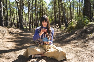 Woman playing a Tibetan singing bowl in the woods