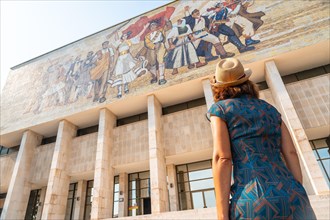 A female tourist looking at the painting of the entrance to the National Historical Museum in Skanderbeg Square in Tirana. Albania