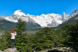 Tourist taking photos with her mobile phone of the glaciated ridge of Cerro Torre in Los Glaciares National Park
