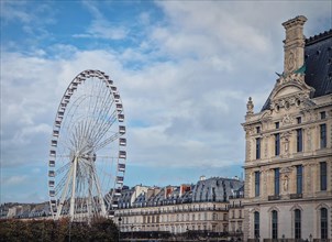 Grande Roue de Paris ferris wheel next to Louvre museum building and parisian houses