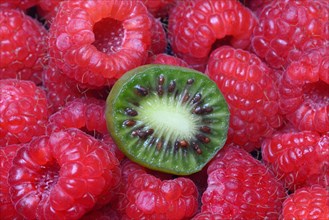 Halved mini kiwi on raspberries