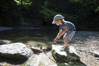 Little boy playing on the bank of the Taugl at the Wald Wasser Zauber Weg near Hintersee
