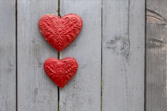 Two red metal hearts on a grey wooden gate