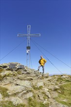 Hiker standing at the summit cross of the Schafsiedel