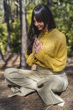 Woman meditates with hands clasped on the woods. Vertical Shot