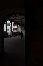 Woman in Silhouette Standing in a Patio with Arches in Church Munsterkirche in Schaffhausen