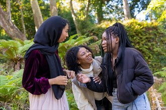 Horizontal photo of a Muslim young woman and african american female friends laughing in a park