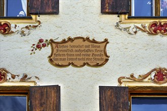Restored old building facade with painted window decorations and motto by Goethe