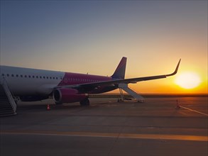Plane ready for boarding at airport with the view to the sunrise. Travel and vacation concept