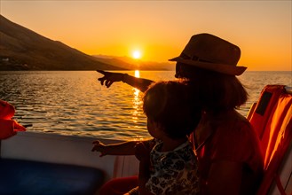 A family enjoying the orange sunset of Shkoder Lake in Shiroka and the mountains. Albania