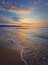 Early morning on the beach with a peaceful view to the sunrise above the sea. Calm seascape dawn scene