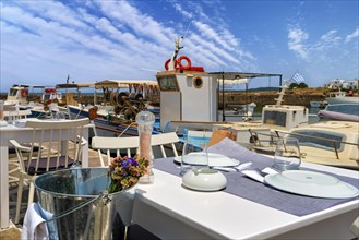 Tables and chairs of seafood restaurant by waterfront of Naoussa bay