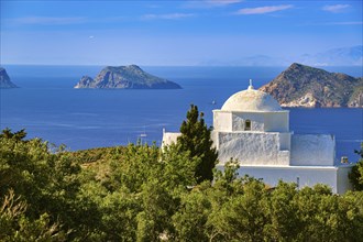 White Greek Orthodox chapel or church on hilltop of seashore on clear blue sky on sunny day. Clear sky