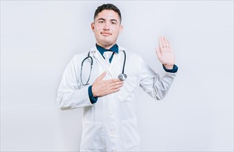 Young doctor raising hand and swearing isolated. handsome doctor making oath and promise isolated