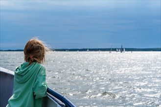Girl on an excursion boat looking towards sailing ships on the Baltic Sea