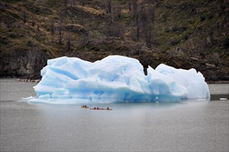 Tourists in kayaks approach an iceberg on Lago Grey in Torres del Paine National Park