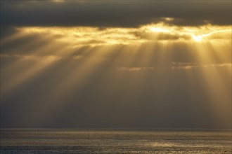 Sunbeams shining through clouds by the sea