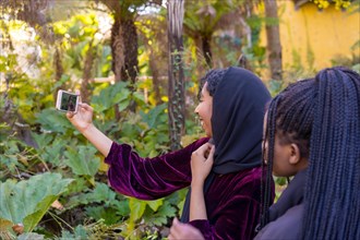 Rear view of a muslim woman taking a selfie with friends in a park