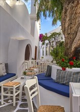 Beautiful outdoor cafe or bar in narrow streets of Greek town on sunny summer day offers refreshing shade under trees