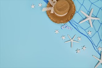 Simple summer banner with straw hat and fishing net and white starfish on blue background with copy space