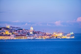 View of Lisbon over Tagus river with moored cruise liner in evening twilight. Lisbon