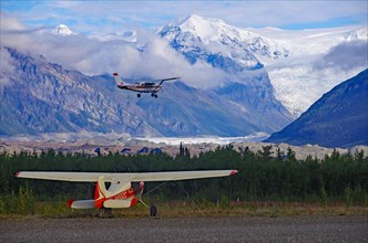 Two small bush planes in front of huge glaciers