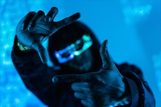 Studio photo with blue neon light of a futuristic man gesturing while wearing augmented reality goggles