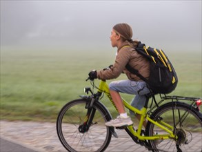 Boy with bicycle and schoolbag through the fog
