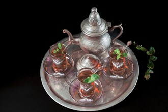 Tray with Moorish tea with mint and silver pitcher and sugar bowl isolated on black background and copy space
