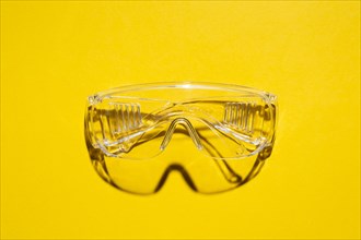 Top view of plastic safety goggles against a yellow background
