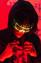Studio portrait with red neon lights of a cool futuristic afro man with smart glasses