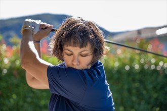 Front View on a Female Golfer Making a Golf Swing in a Sunny Day in Switzerland