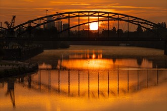 The sun rises behind the Deutschherrn Bridge