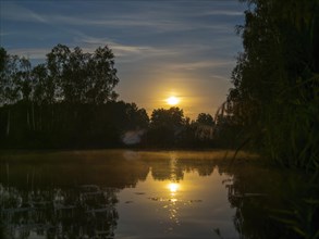 Full moon setting at the lake
