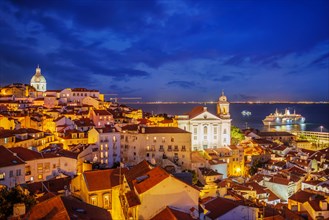 View of Lisbon famous view from Miradouro de Santa Luzia tourist viewpoint over Alfama old city district at night with cruise liner. Lisbon