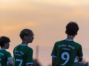 Young football players after the match in front of evening sky